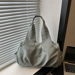 Grand sac fourre-tout en nylon vert sauge pour femme posé sur un bureau de bureau moderne