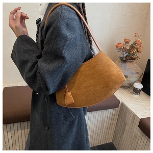 Détail du sac sous le bras en faux daim marron avec bandoulière et pendentif décoratif