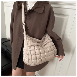 Dettaglio della borsa a tracolla beige trapuntata con texture in nylon e tasca laterale