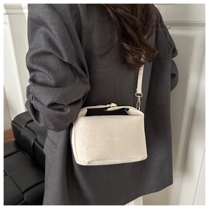 Detail of cream white leather bucket bag with animal embossed texture and gold buckle