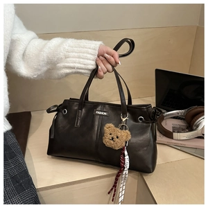 Detail of vintage dark brown wax leather tote with fashion tag and cute bear pendant