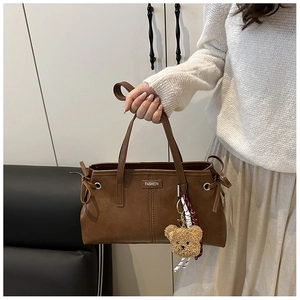 Detail of vintage oil wax leather tote bag with fashion tag and cute teddy bear charm