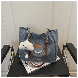 Dettaglio borsa tote in denim blu con tracolla in pelle e ciondolo a nuvola di peluche