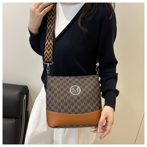 Detail of canvas crossbody bag with letter print and silver M logo on a model