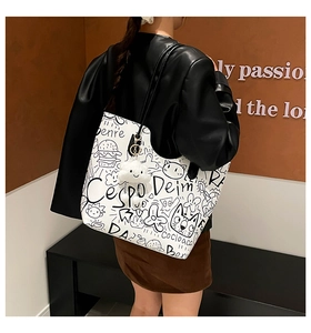 Dettaglio della borsa tote bianca con graffiti neri e un ciondolo a forma di nuvola