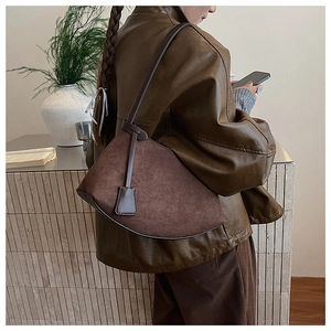 Détail d'un sac à bandoulière en daim marron foncé porté avec une tenue d'automne rétro