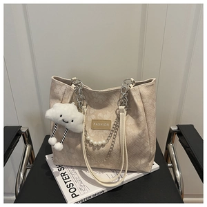 Dettaglio della borsa tote jacquard con motivi floreali, catena di perle e ciondolo