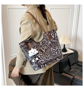 Detail of coffee brown tote bag with white cat graffiti print and cloud plush pendant