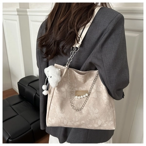 Dettaglio della borsa tote beige a fiori con catena di perle e ciondolo a nuvola soffice