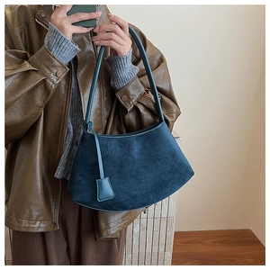Detailed view of deep blue suede hobo bag with irregular curved shape and long shoulder strap