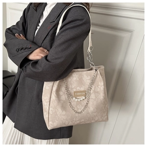 Dettaglio borsa tote beige in jacquard floreale con catena di perle e finiture chic
