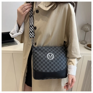 Detail of black monogram crossbody bag with round metal M logo and geometric wide strap