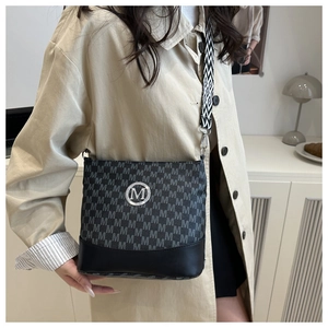 Detail of crossbody bucket bag featuring M-letter print and geometric woven strap