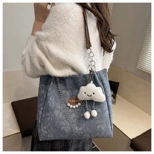 Dettaglio della borsa tote a fiori blu con etichetta in pelle, perle e ciondolo
