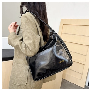Detail of a large black glossy shoulder bag with Fashion lettering on the side
