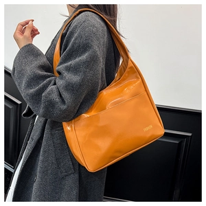 Detail of a bright orange patent leather tote bag with FASHION logo on wool coat
