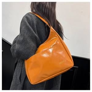 Close-up of bright orange glossy PU leather hobo bag worn with a grey herringbone coat