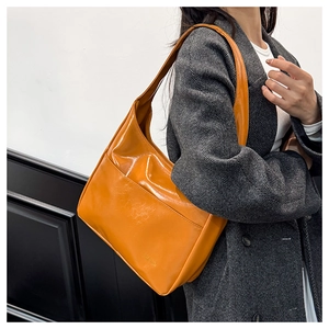 Close-up of bright yellow glossy leather shoulder bag with functional front pocket