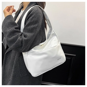 Detail of white glossy faux leather hobo bag worn over the shoulder on a grey wool coat
