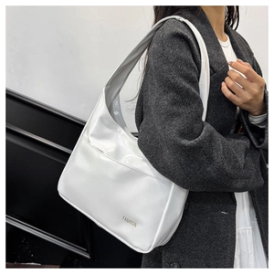 Detail view of white leather shoulder bag with gold FASHION logo on a textured coat