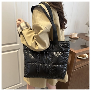 Detail of a black quilted tote bag showing padded stitching and glossy nylon material
