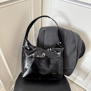 Large vintage black tote bag in glossy leather with gold FASHION lettering on a chair
