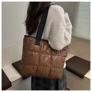 Rear view of brown quilted down tote bag with black nylon straps for autumn fashion