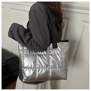 Silver quilted tote bag with metallic finish and square patterns shown on model shoulder