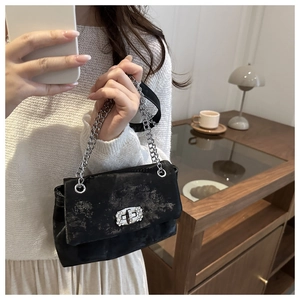 Detail of black pleated chain bag with silver textures and rhinestone buckle lock