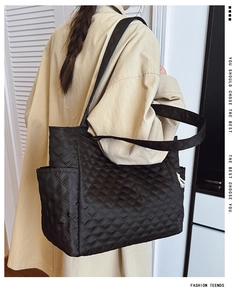 Detail view of black quilted tote bag with side pocket and spacious nylon fabric interior