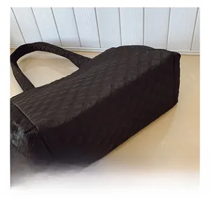 Detail view of the black quilted nylon fabric texture and stitching on large tote bag