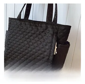 Detail of black quilted tote bag with smooth zipper and side pocket for extra storage