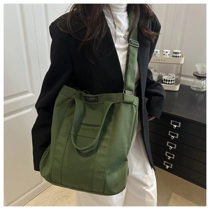Détail du sac fourre-tout en toile vert forêt avec sangle réglable et étiquette tissée