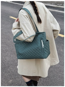 Outdoor shot showing side pocket and quilted nylon texture of dark green tote bag