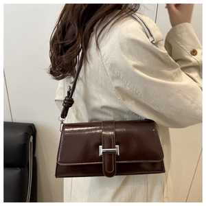 Detail of dark brown leather square shoulder bag with silver buckle and knotted strap