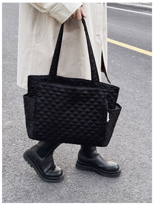Close-up of black quilted tote bag with side pocket and sleek nylon material texture