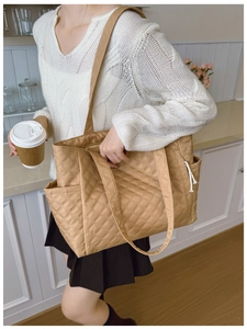 Close-up of khaki quilted tote bag with side pockets and white drawstrings in home setting