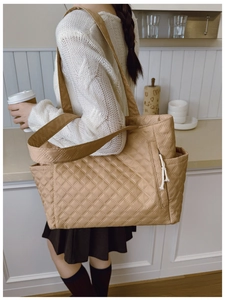 Detail of khaki quilted tote bag with side zipper and rope puller on shoulder strap