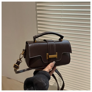 Detail of vintage dark brown faux leather crossbody bag with metallic clasp and top handle
