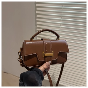 Detail of brown matte crossbody bag with curved handle and metal snap closure
