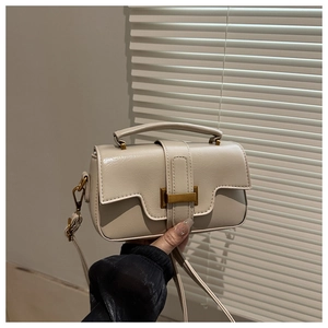 Close-up of cream square crossbody bag featuring matte gold hardware and textured PU leather