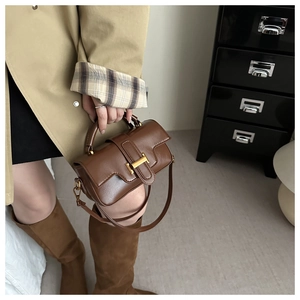 Brown crossbody handbag detail showing glossy leather texture and golden H-shaped clasp