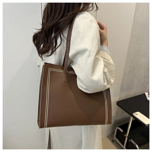 Close-up of brown pebbled leather tote bag with elegant white beaded rectangular pattern