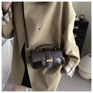 Detail of dark brown retro crossbody bag featuring oily leather texture and gold buckle