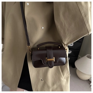 Détail du sac à bandoulière en cuir marron foncé avec boucle dorée et coutures apparentes