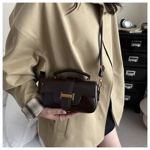 Détail d'un sac bandoulière vintage marron foncé avec boucle dorée et texture cuir lisse