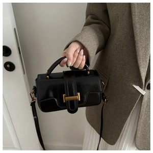 Detail of vintage black patent leather mini square bag with gold buckle and top handle