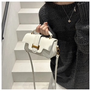 Close-up of white leather handbag with golden H-shaped clasp held by model