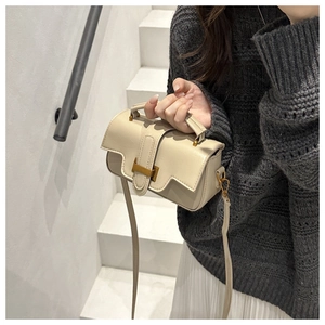 Détail d'un sac à main crème avec fermoir métallique doré et texture cuir premium