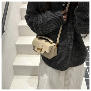 Détail du mini sac bandoulière crème avec boucle H dorée sur tenue en tricot